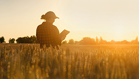 A woman in a field holding an iPad.