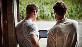 Two farmers looking at an iPad and discussing field data